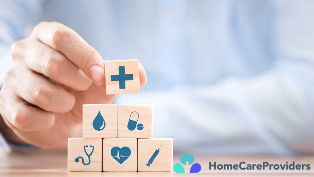 A close-up view of a hand holding wooden blocks labeled with medicine and insurance terms.