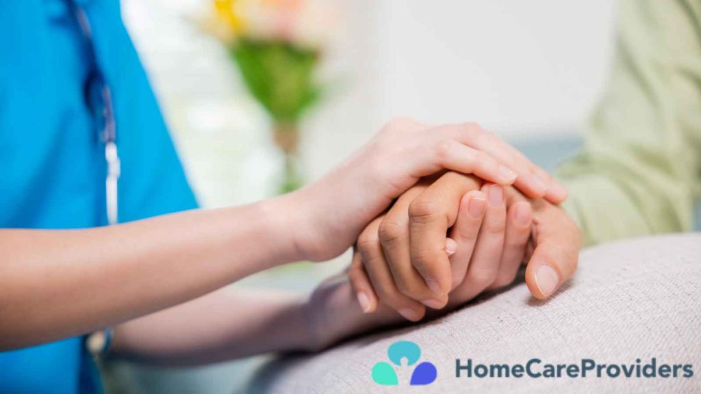 A close-up of a nurse’s hand gently holding an elderly patient’s hand.