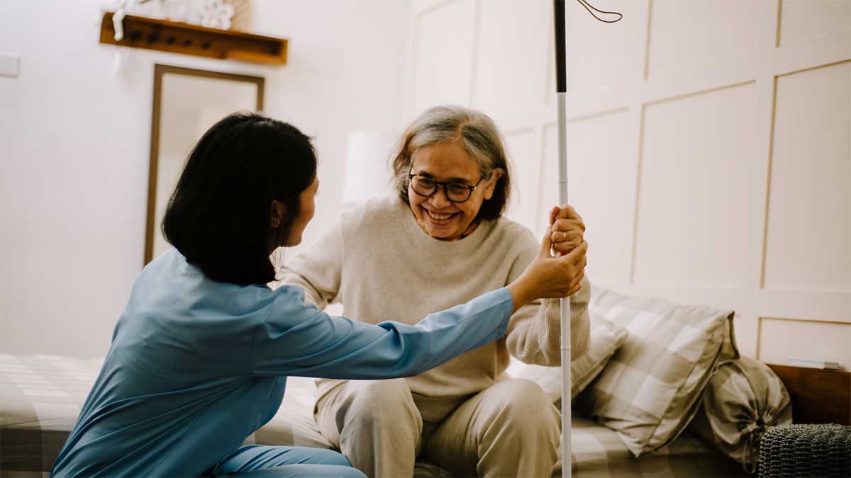 A nurse carefully assisting an elderly woman to get out of bed,