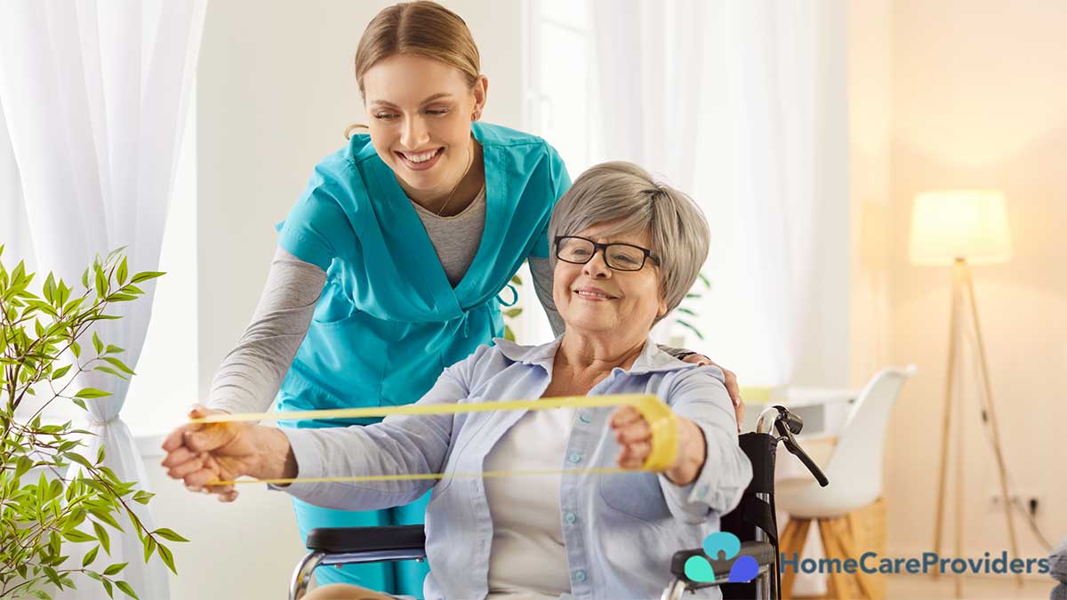 A nurse guiding an elderly woman through gentle physical exercises in her home