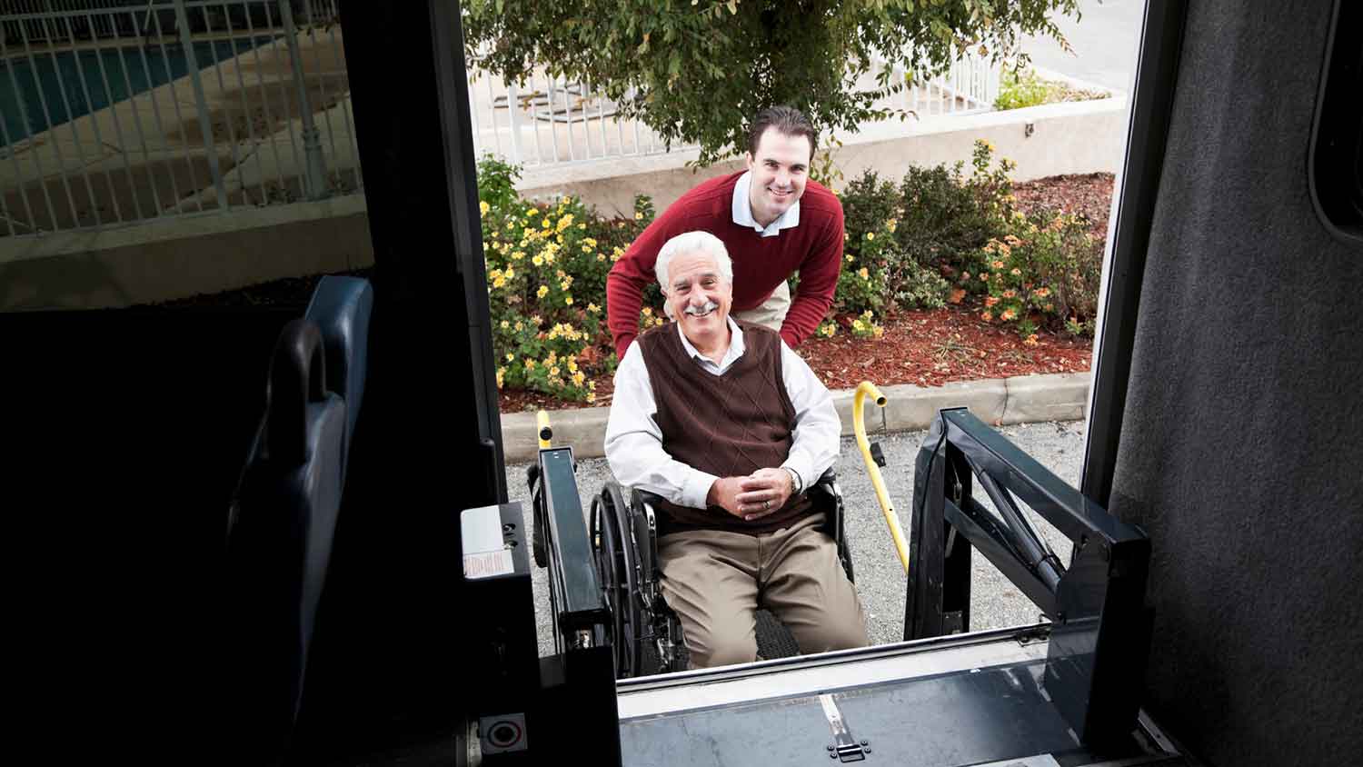 An elderly woman being helped by a caregiver to get into a vehicle