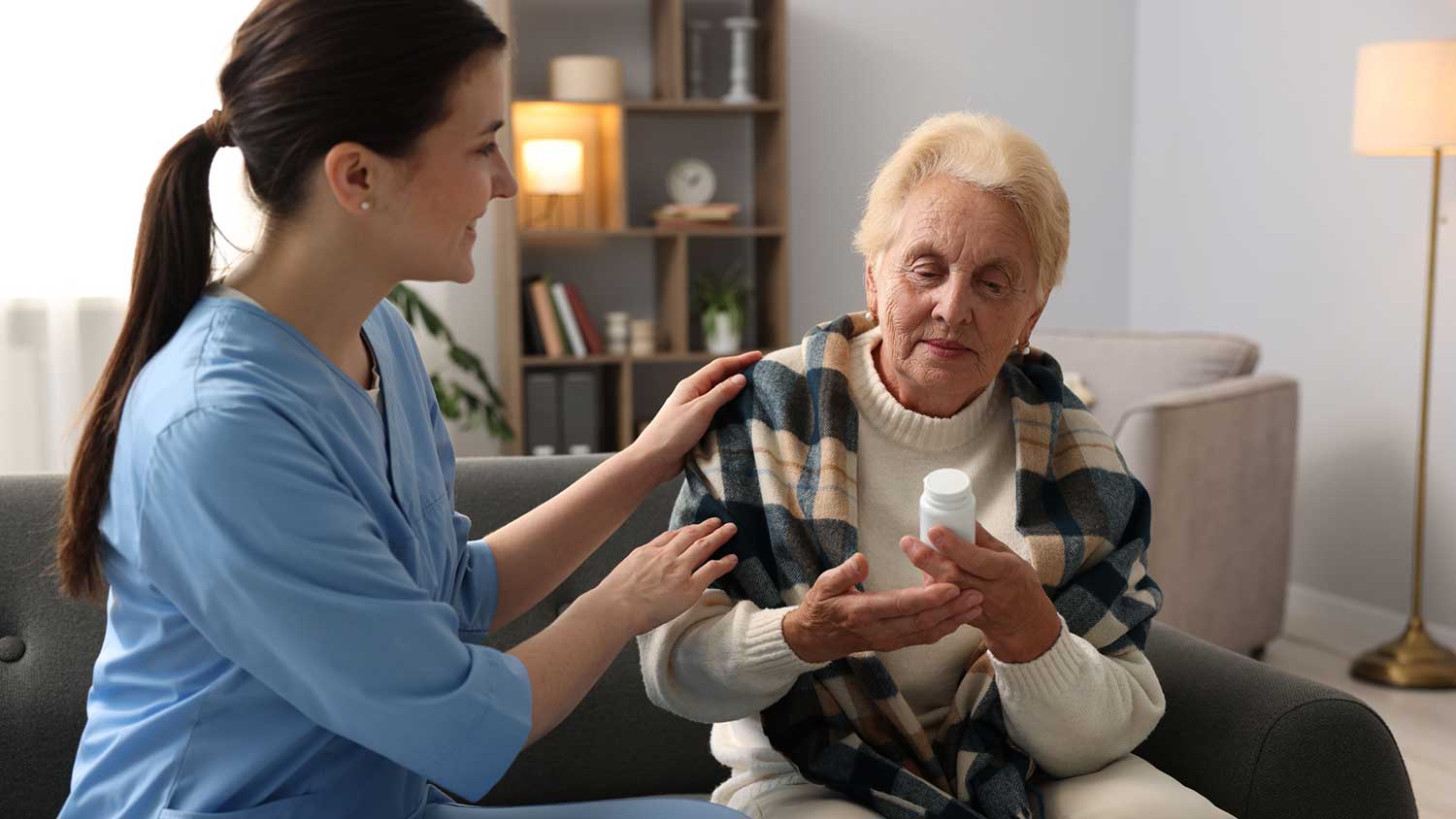 A nurse assisting an elderly woman with her medication at home