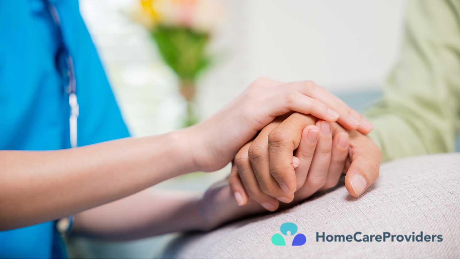 Close-up of a nurse gently holding a patient’s hand for support